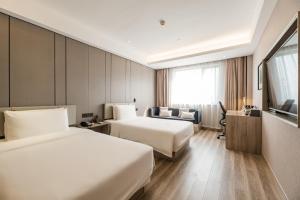 um quarto de hotel com duas camas e um sofá em Atour Hotel Hangzhou Huanglong em Hangzhou