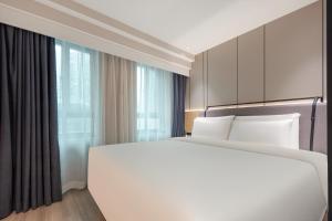 Atour X Hotel Shanghai Xujiahui Sports Center في شانغهاي: غرفة نوم بسرير ابيض كبير ونافذة