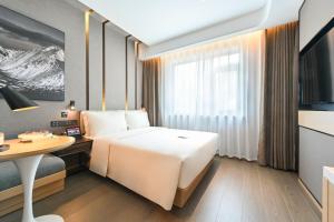 Habitación de hotel con cama, escritorio y mesa. en Atour Hotel Beijing Drum Tower, en Beijing