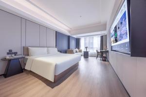 Schlafzimmer mit einem großen weißen Bett und einem Flachbild-TV in der Unterkunft Atour X Hotel Shenzhen Luohu Sungang Baoneng Center in Shenzhen
