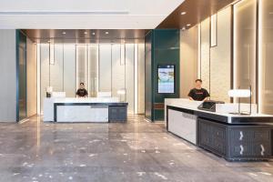 dos hombres sentados en un escritorio en el vestíbulo en Atour Hotel Guangzhou Zhongcun Hanxi Changlong Metro Station, en Guangzhou