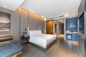 a bedroom with a white bed and a couch at Atour Hotel Zhijiang Bridge in Hangzhou