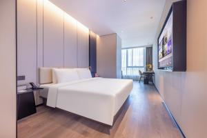una camera da letto con un grande letto bianco e una televisione di Atour Hotel Beijing Beiqing Road Yongfeng Science and Technology Park a Pechino
