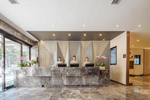 three people sitting at a reception desk in a lobby at Atour X Hotel Kunming Cultural Palace East Renmin Road in Kunming