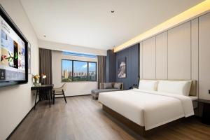 Habitación de hotel con cama blanca y TV en Atour Hotel Huizhou Huiyang New Metropolis, en Huizhou