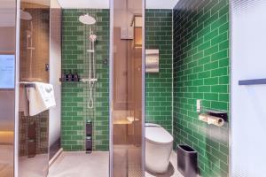 La salle de bains est pourvue de carrelage vert, de toilettes et d'une douche. dans l'établissement Atour X Hotel Beijing Majiabao Subway Station, à Pékin