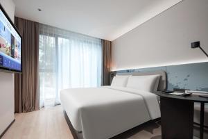 a large white bed in a room with a tv at Atour Light Hotel Shenzhen Nanshan Raffles City Plaza in Shenzhen