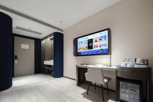 a room with a desk and a television on a wall at Atour Light Hotel Hangzhou West Lake Huanshan Road in Hangzhou