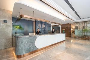 two people sitting at a reception desk in a lobby at Atour X Hotel Shanghai Bund East Nanjing Road Pedestrian Street in Shanghai