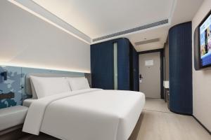 1 dormitorio con 1 cama blanca y TV en Atour Light Hotel Hangzhou West Lake Huanshan Road en Hangzhou