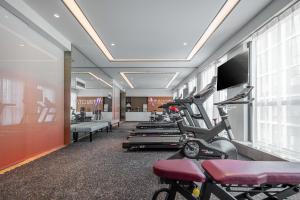a gym with treadmills ellipticals and a flat screen tv at Atour Hotel Hangzhou East Railway Station East Square in Hangzhou