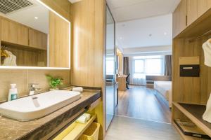 a bathroom with a sink and a bedroom at Atour Hotel Hangzhou Zhuantang Songcheng Academy of Fine Arts in Hangzhou