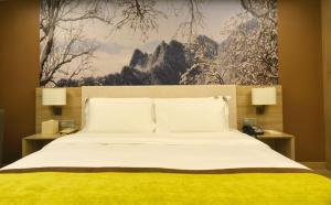 Atour Hotel Xi'an Xiaozhai Petroleum University في شيان: غرفة نوم بسرير كبير ومصبغتين ولوحة