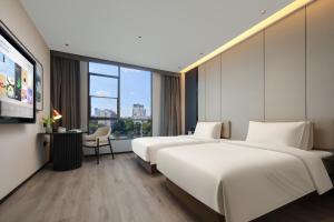 a hotel room with two beds and a tv at Atour Hotel Xiamen Xiang'an Torch Industrial Park in Xiang'an