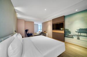 1 dormitorio con 1 cama blanca grande y una pintura grande en Atour Hotel Hangzhou Huanglong Wanke Xueyuan Road en Hangzhou