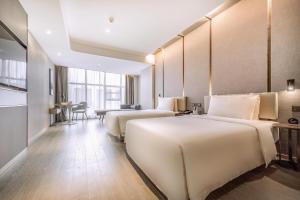 a hotel room with two beds and a table at Atour Hotel Guangzhou Panyu City Bridge in Guangzhou