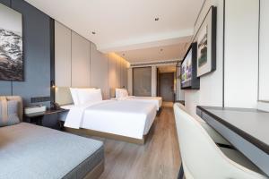 a hotel room with two beds and a tv at Atour Hotel Guangzhou Zhujiang New Town Taikoo Hui in Guangzhou