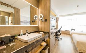 a bathroom with a sink and a bed and a mirror at Atour Hotel Kunming Dashanghui in Kunming