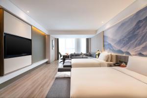 ein Hotelzimmer mit 2 Betten und einem Flachbild-TV in der Unterkunft Atour Hotel Xi'an Daming Palace in Xi'an