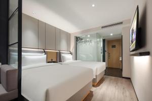 um quarto de hotel com duas camas e uma televisão em Atour X Hotel Shanghai Xujiahui Sports Center em Xangai