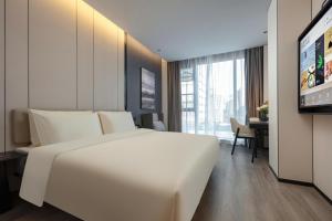 sypialnia z dużym białym łóżkiem i biurkiem w obiekcie Atour Hotel Hangzhou Zhejiang University Xilianqiao w mieście Hangzhou