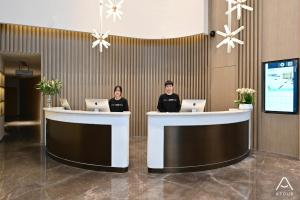 two people sitting at a counter in a lobby at Atour Hotel Beijing Lishuiqiao in Changping