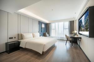Atour Hotel Chengdu Wuhou West Intelligent Valley في تشنغدو: غرفة نوم بسرير ابيض كبير وتلفزيون