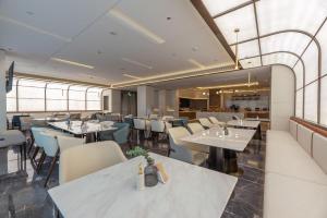 un restaurante con mesas y sillas blancas y ventanas en Atour S Hotel Xiamen Cross-Strait Financial Center, en Xiamen