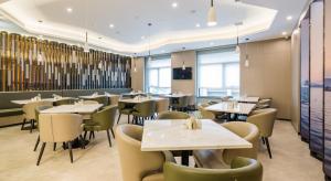 a restaurant with tables and chairs in a room at Atour Hotel Hangzhou Zhuantang Songcheng Academy of Fine Arts in Hangzhou