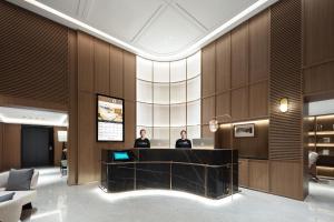 two people standing at a desk in a lobby at Atour Hotel Shanghai Lujiazui South Pudong Road in Shanghai