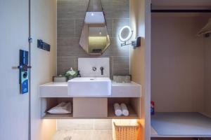 een badkamer met een witte wastafel en een spiegel bij Atour Hotel Shenzhen Nanshan Xili University Town in Shenzhen