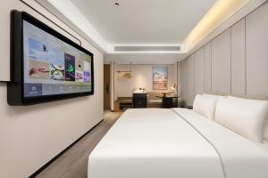 Schlafzimmer mit einem großen weißen Bett und einem Flachbild-TV in der Unterkunft Atour Hotel Xi'an Bell Tower Dacha City Metro Station in Xi'an