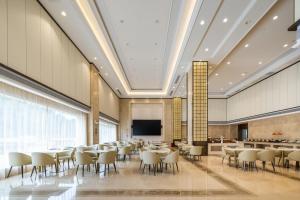 a conference room with tables and chairs and a screen at Atour X Hotel Shenzhen Baoan Airport Aviation City in Bao'an