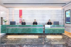 three people sitting at a desk in a lobby at Atour Hotel Beijing Beiqing Road Yongfeng Science and Technology Park in Beijing