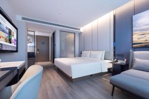 Atour Hotel Kunming Yunnan-Burma Avenue في كونمينغ: غرفة نوم بسرير ابيض كبير وكرسيين
