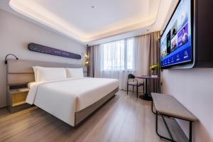 um quarto de hotel com uma cama e uma televisão de ecrã plano em Atour Light Hotel Shanghai Lujiazui Financial Center em Xangai