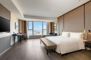 een hotelkamer met een groot bed en een groot raam bij Atour Hotel Dongguan Fenggang in Qinglinjing