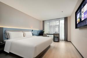 杭州的住宿－杭州西湖武林广场环城北路轻居酒店，卧室配有一张白色大床和一台平面电视。