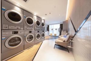 a laundry room with multiple washing machines and a chair at Atour Hotel Foshan Shunde Happy Coast in Shunde