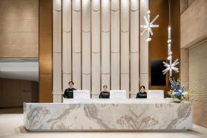 three women sitting at a reception desk in a lobby at Atour Hotel Chengdu Wuhou West Intelligent Valley in Chengdu