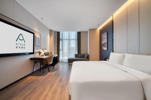 a hotel room with a white bed and a desk at Atour Hotel Hangzhou Jiubao Passenger Transport Center Jiutian Huanbei in Hangzhou