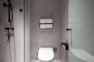a bathroom with a toilet and a shower with towels at Atour Light Hotel Hangzhou West Lake Huanshan Road in Hangzhou