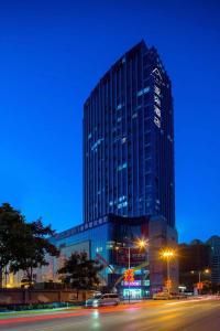 ein hohes Gebäude in der Nacht mit einer Straße davor in der Unterkunft Atour Hotel Xi'an Daming Palace in Xi'an