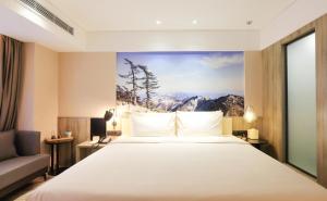 una habitación de hotel con una cama y un cuadro en la pared en Atour Hotel Xi'an Xixian Vientiane City en Xi'an