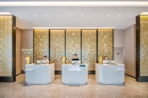 a lobby with three people sitting at tables with laptops at Atour Hotel Dongguan Humen Avenue in Dongguan