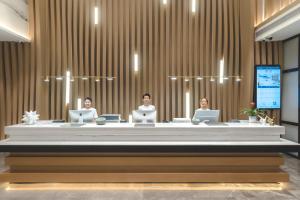 three people sitting at a long table with laptops at Atour Hotel Zhanjiang Renmin Avenue Dingsheng Plaza in Zhanjiang