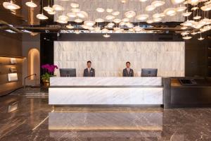 Atour Hotel Shenzhen Futian CBD Civic Center في شنجن: رجلان يقفان خلف طاولة بيضاء كبيرة في بهو الفندق