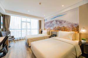 昆明市にあるAtour Hotel Kunming Dashanghuiのベッド2台とデスクが備わるホテルルームです。