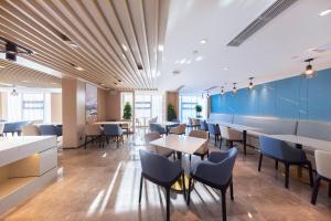 un restaurante con paredes azules, mesas y sillas en Atour Hotel Kunming South High Speed ​​Railway Station University Town, en Kunming