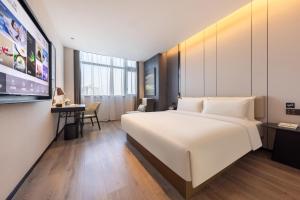 a hotel room with a large white bed and a desk at Atour Hotel Hangzhou Xiaoshan South Railway Station Xiaoshan Road in Xiaoshan